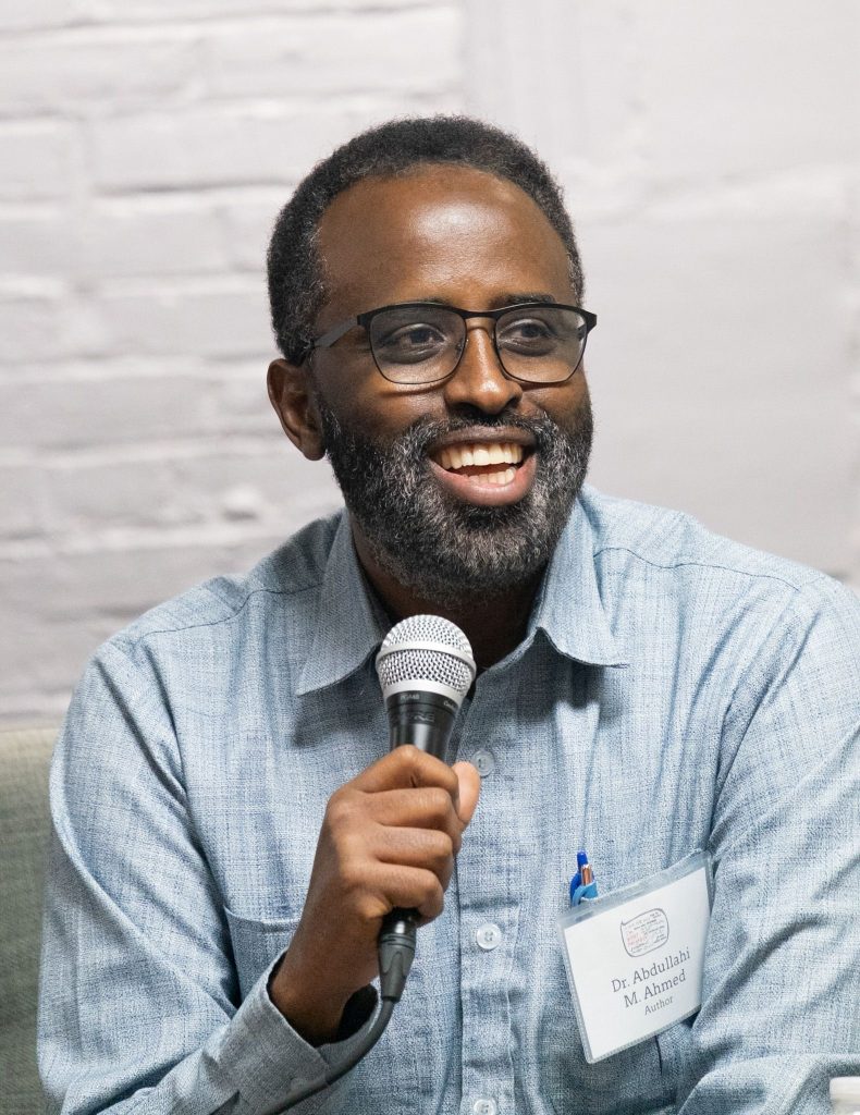Dr. Abdullahi Ahmed smiling and holding a microphone